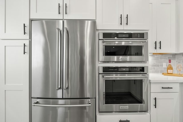 kitchen with appliances with stainless steel finishes, tasteful backsplash, and white cabinets