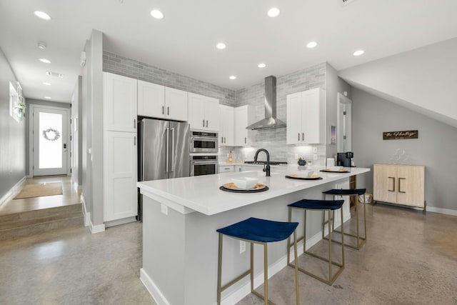 kitchen featuring kitchen peninsula, white cabinets, a kitchen breakfast bar, and wall chimney exhaust hood