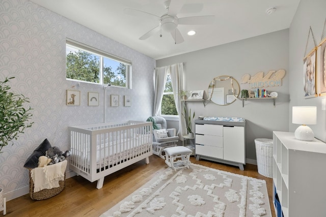 bedroom featuring ceiling fan, light hardwood / wood-style flooring, and a crib