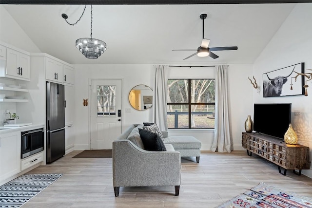 200 Shady River Rd, Wimberley, TX 78676 - living room featuring a ceiling fan, vaulted ceiling, a chandelier, light wood-style floors, and baseboards