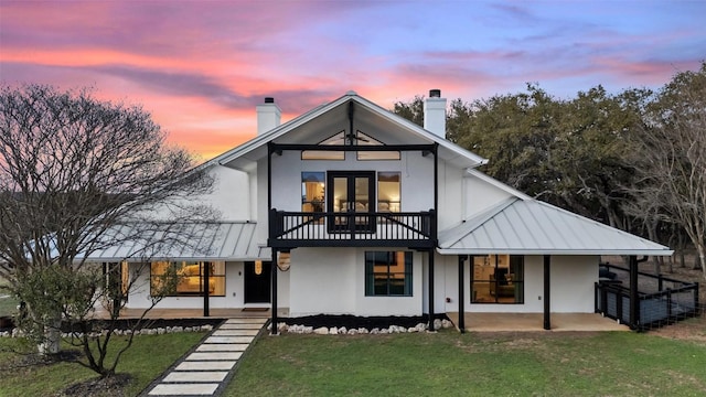 200 Shady River Rd, Wimberley, TX 78676 - back of property at dusk with a chimney, a balcony, and metal roof
