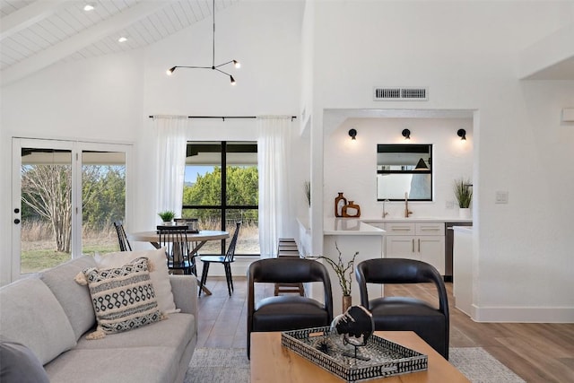 living room with beam ceiling, light wood finished floors, a healthy amount of sunlight, visible vents, and wood ceiling