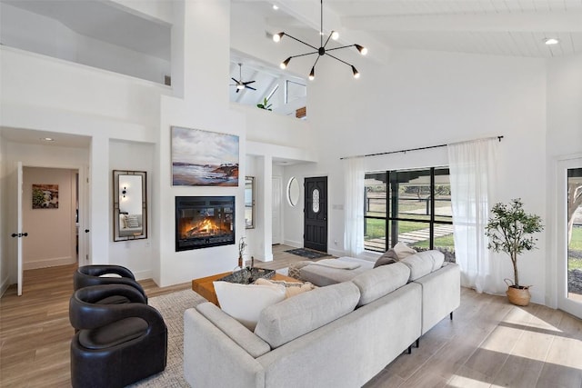 200 Shady River Rd, Wimberley, TX 78676 - living room with healthy amount of natural light, a glass covered fireplace, light wood-type flooring, high vaulted ceiling, and beamed ceiling