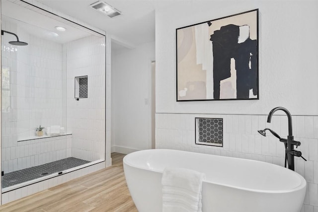 200 Shady River Rd, Wimberley, TX 78676 - full bath featuring wood finished floors, a freestanding bath, a tile shower, and tile walls