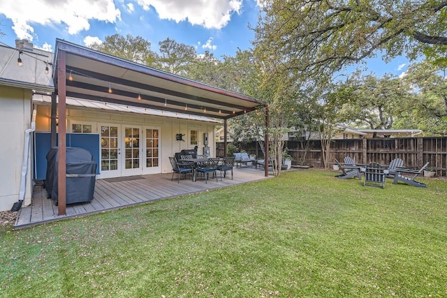 rear view of house with a lawn, french doors, and a wooden deck