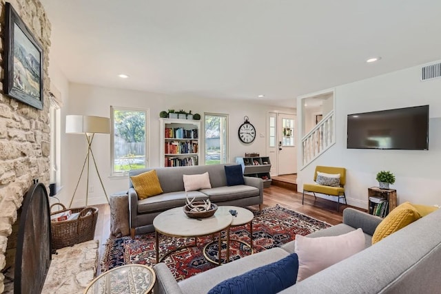 living room with a stone fireplace, a wealth of natural light, and hardwood / wood-style floors