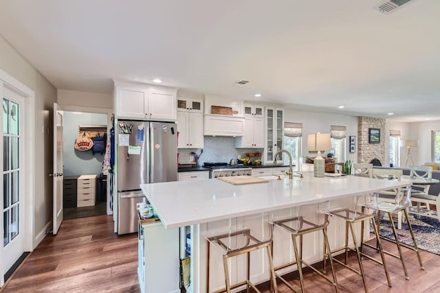 kitchen with a breakfast bar, a spacious island, stainless steel fridge, white cabinets, and dark hardwood / wood-style floors