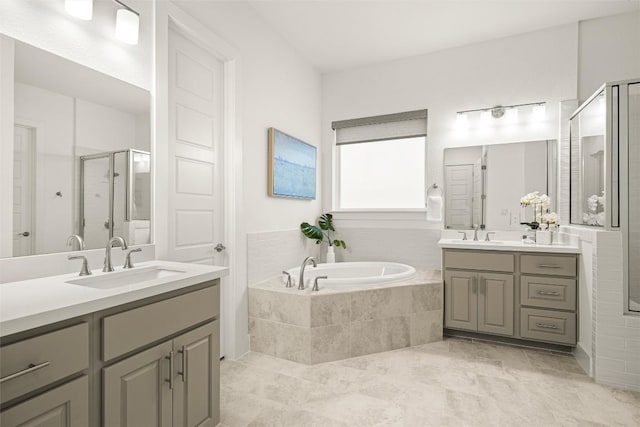 bathroom featuring two vanities, a garden tub, a stall shower, and a sink