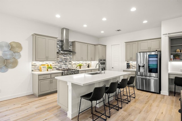 kitchen with wall chimney range hood, visible vents, stainless steel appliances, and gray cabinets