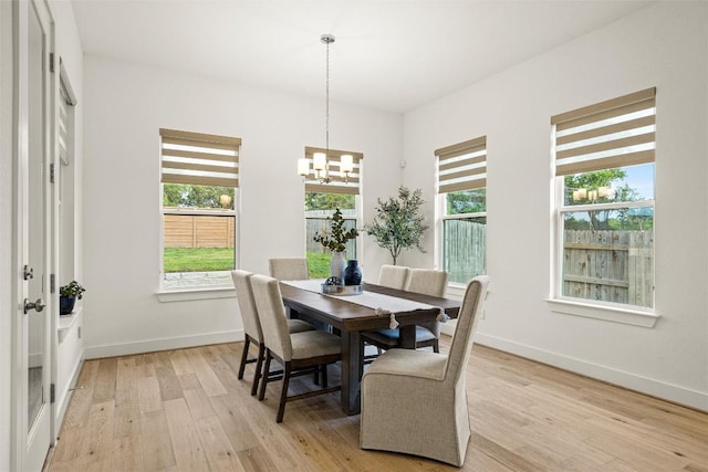 dining area featuring a healthy amount of sunlight, baseboards, a notable chandelier, and light wood finished floors