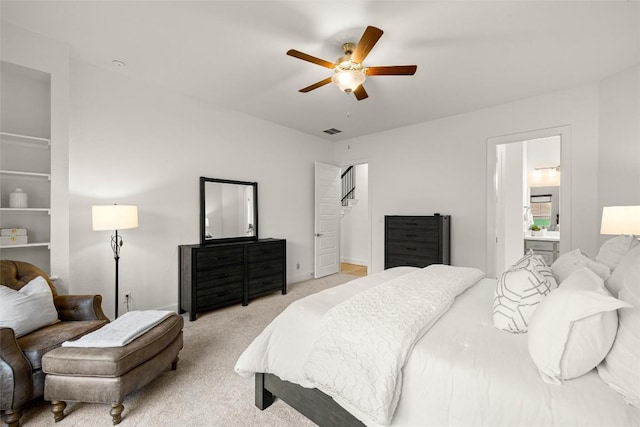 carpeted bedroom with baseboards, visible vents, a ceiling fan, and ensuite bath