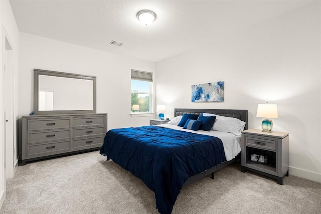 bedroom with baseboards, visible vents, and light colored carpet