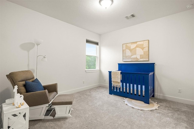carpeted bedroom featuring visible vents, a crib, and baseboards