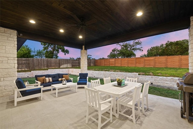 patio terrace at dusk featuring ceiling fan, an outdoor hangout area, outdoor dining area, and a fenced backyard