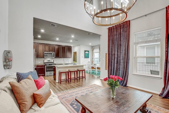 living room featuring sink, light wood-type flooring, and a high ceiling