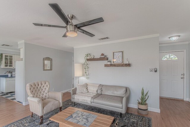 living room with visible vents, crown molding, and light wood-style flooring