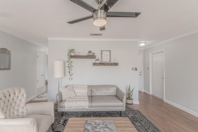 living area with visible vents, baseboards, a ceiling fan, ornamental molding, and wood finished floors