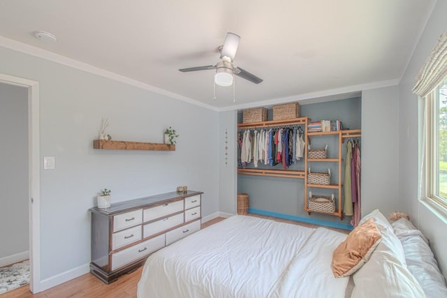 bedroom with crown molding, light wood finished floors, a closet, ceiling fan, and baseboards