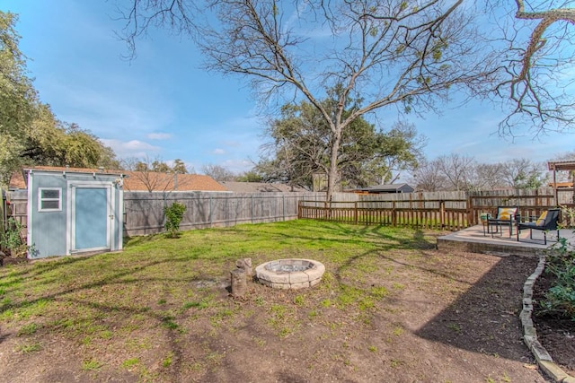 view of yard featuring an outbuilding, a patio, a fenced backyard, a fire pit, and a storage shed