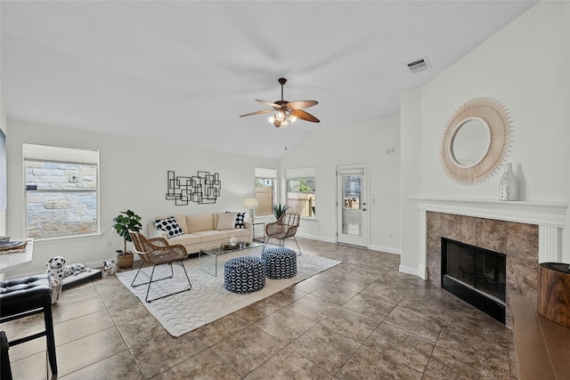 living area featuring visible vents, lofted ceiling, a ceiling fan, a tiled fireplace, and baseboards