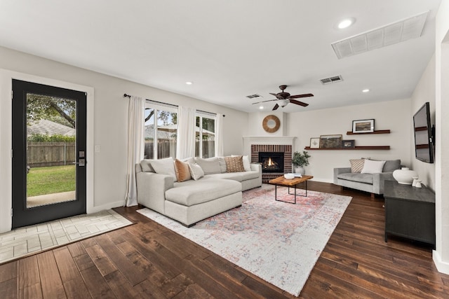 living room with a fireplace, ceiling fan, and dark hardwood / wood-style flooring