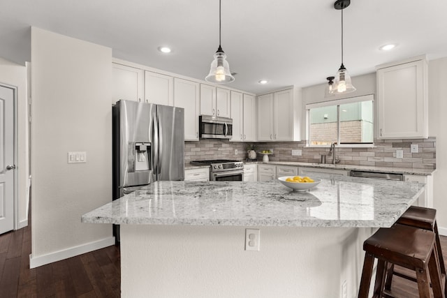 kitchen featuring appliances with stainless steel finishes, a kitchen island, white cabinets, and decorative light fixtures