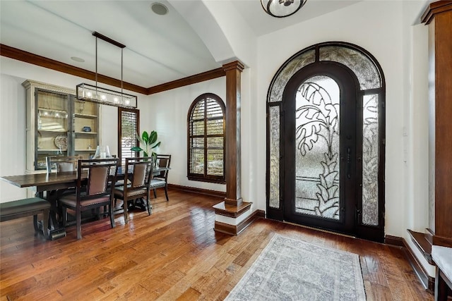 foyer entrance featuring ornate columns, baseboards, arched walkways, and wood finished floors