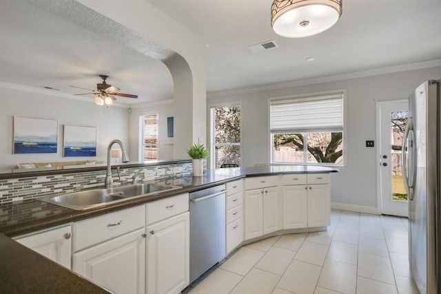 kitchen featuring dark countertops, appliances with stainless steel finishes, white cabinetry, and a sink