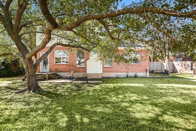 view of front of house featuring a front lawn, brick siding, and fence