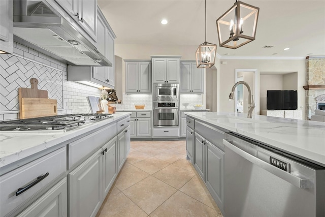 kitchen with appliances with stainless steel finishes, crown molding, extractor fan, hanging light fixtures, and gray cabinetry