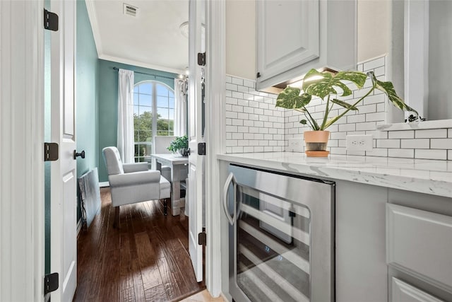 interior space featuring dark wood finished floors, ornamental molding, decorative backsplash, beverage cooler, and visible vents