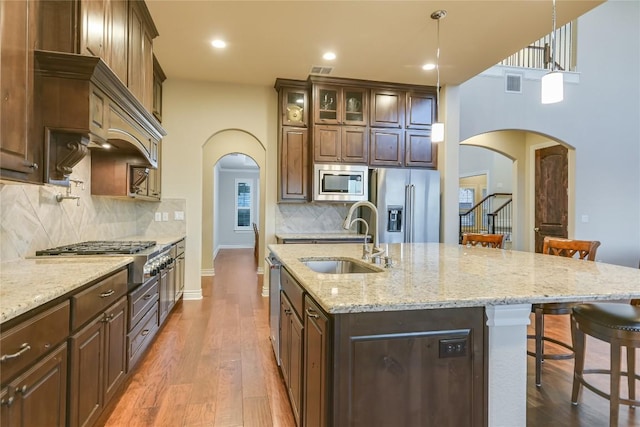 205 Palazza Alto Dr, Austin, TX 78734 - kitchen with a sink, stainless steel appliances, a kitchen breakfast bar, arched walkways, and light stone counters