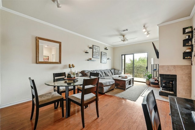 dining room featuring ornamental molding, ceiling fan, hardwood / wood-style flooring, and a fireplace