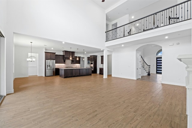 2324 Bel Paese Bnd, Leander, TX 78641 - unfurnished living room with a high ceiling, light wood-type flooring, stairs, and arched walkways