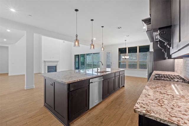 2324 Bel Paese Bnd, Leander, TX 78641 - kitchen with appliances with stainless steel finishes, light wood-style flooring, a fireplace, a spacious island, and recessed lighting