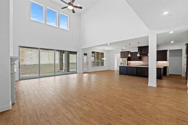 2324 Bel Paese Bnd, Leander, TX 78641 - unfurnished living room with a ceiling fan, a high ceiling, light wood finished floors, and recessed lighting
