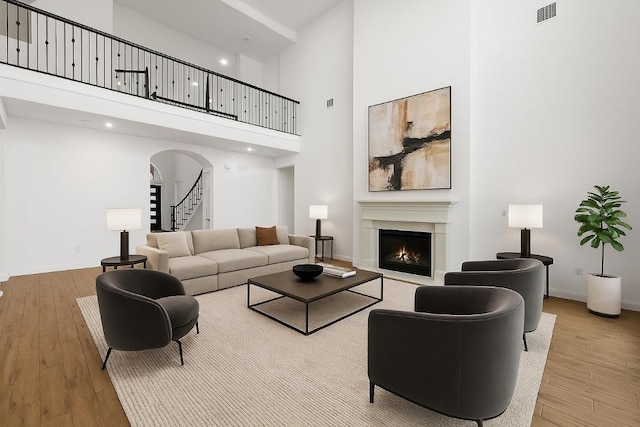 2324 Bel Paese Bnd, Leander, TX 78641 - living room featuring a towering ceiling, wood finished floors, a warm lit fireplace, stairs, and arched walkways