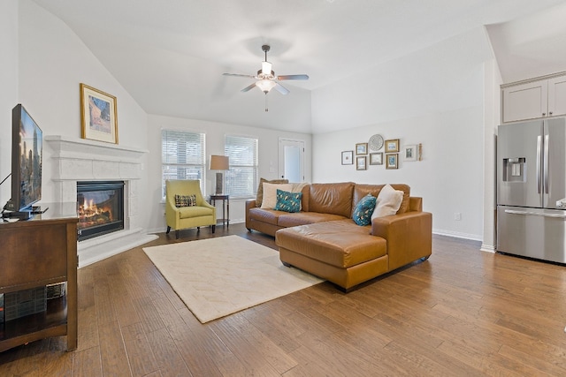 living room with lofted ceiling, ceiling fan, a fireplace, and light hardwood / wood-style floors