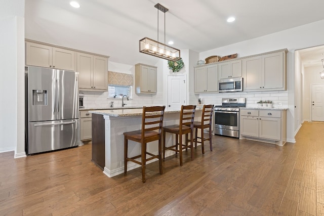 kitchen featuring a kitchen breakfast bar, hanging light fixtures, stainless steel appliances, dark hardwood / wood-style floors, and a kitchen island