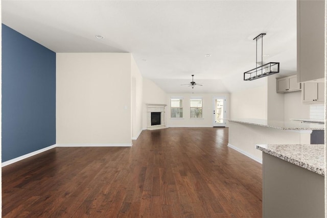 4131 Van Ness Ave, Round Rock, TX 78681 - unfurnished living room with ceiling fan, dark wood-type flooring, baseboards, and a fireplace with raised hearth