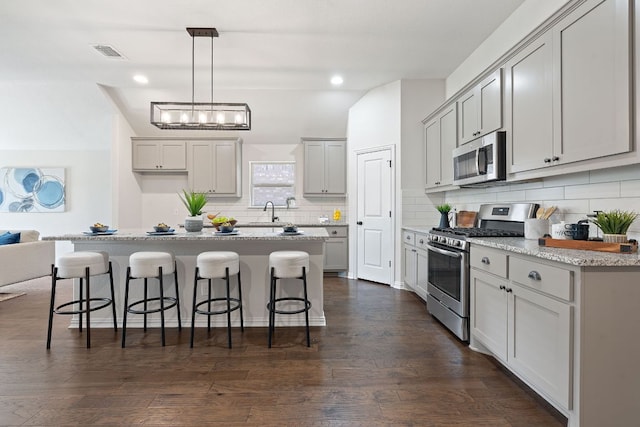 4131 Van Ness Ave, Round Rock, TX 78681 - kitchen with stainless steel appliances, a kitchen breakfast bar, backsplash, dark wood-type flooring, and recessed lighting