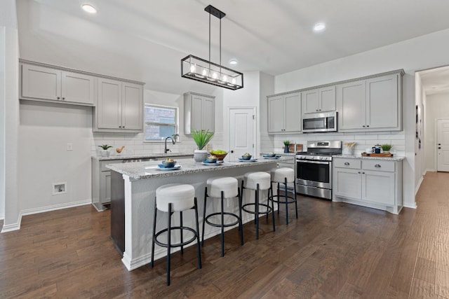 4131 Van Ness Ave, Round Rock, TX 78681 - kitchen featuring stainless steel appliances, backsplash, a center island, a breakfast bar area, and recessed lighting