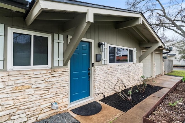 property entrance featuring an attached garage and stone siding