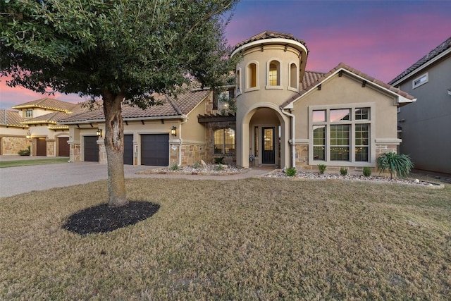 mediterranean / spanish home with stucco siding, driveway, a tiled roof, and stone siding