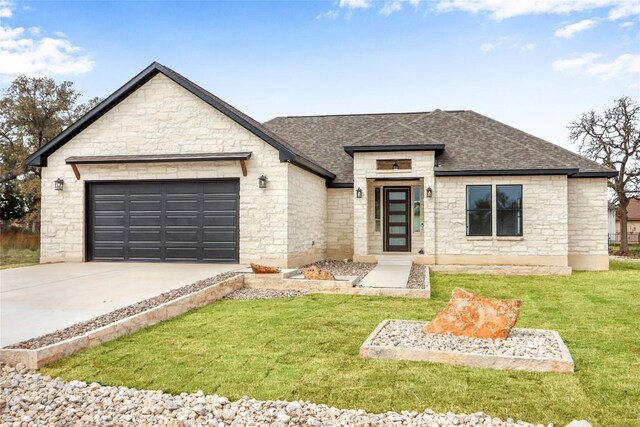 view of front of home featuring roof with shingles, a garage, driveway, and a front yard
