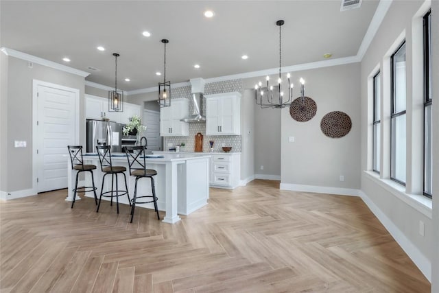 kitchen with light countertops, hanging light fixtures, stainless steel fridge, white cabinetry, and a large island with sink