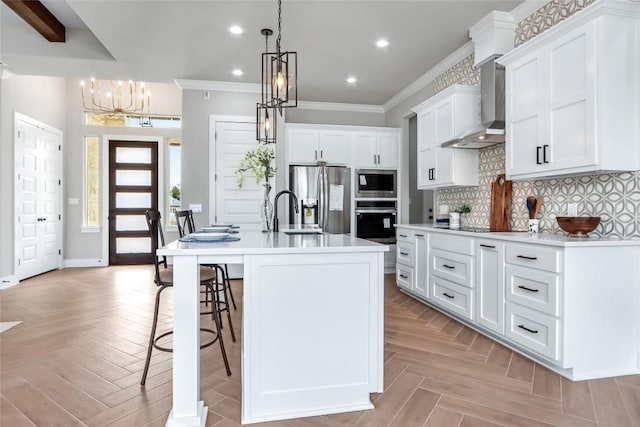 kitchen featuring hanging light fixtures, white cabinets, light countertops, stainless steel appliances, and a center island with sink