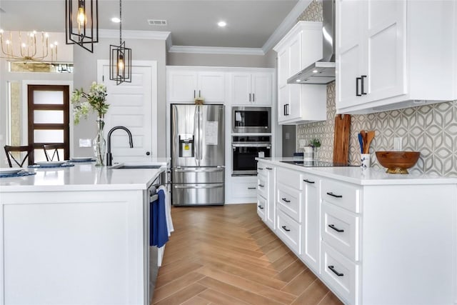kitchen featuring appliances with stainless steel finishes, wall chimney range hood, light countertops, a sink, and white cabinets