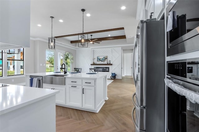 kitchen featuring a sink, hanging light fixtures, light countertops, white cabinetry, and stainless steel appliances