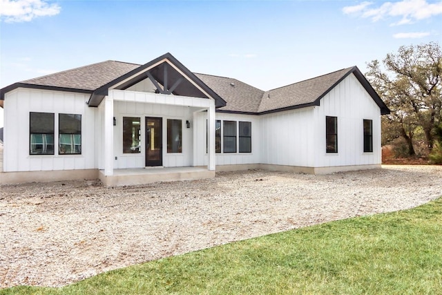 view of front of home featuring a patio, a front lawn, a shingled roof, and board and batten siding